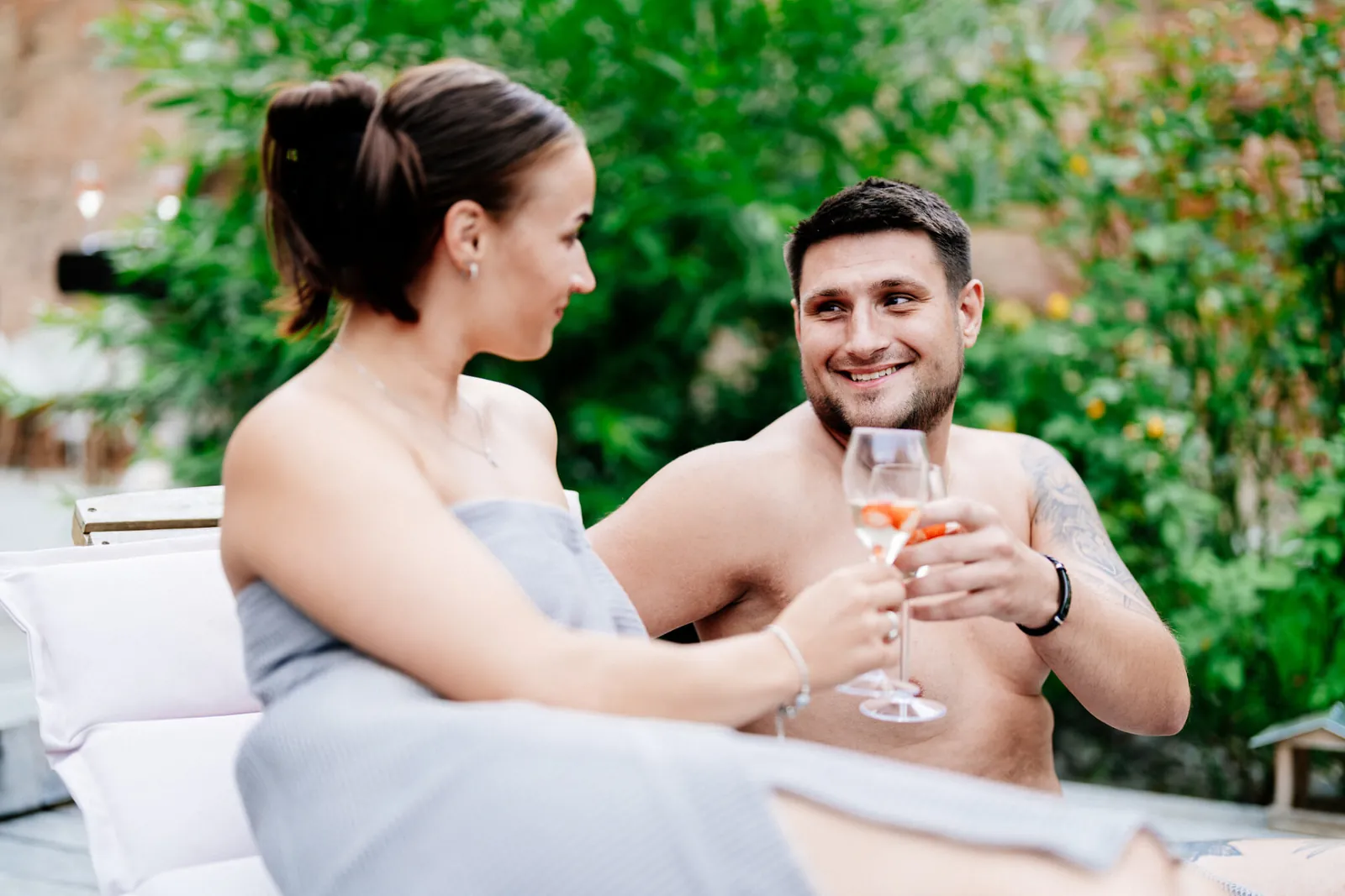 Pár na lehátkách u bazénu s přípitkem v privátním wellness AUROOM